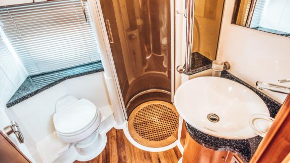Helles Bad mit Holzboden, Duschkabine und modernem Waschbecken.