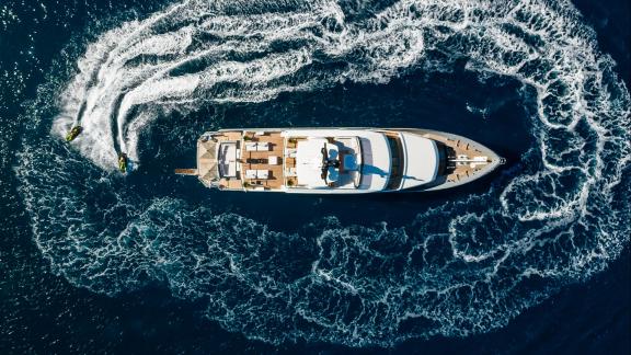 Zwei Jetskis ziehen Kreise um die festliegende Yacht Illusion 2 vor Bodrums Küste aus der Luftperspektive.