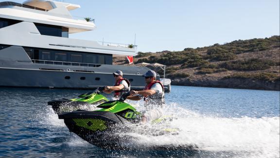 Vor der vor Anker liegenden Illusion 2 genießen zwei Personen Jetski-Action in Bodrums Bucht.