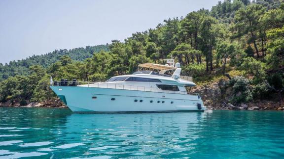 Kuum motor yacht anchored in Bodrum, with a green forest in the background.