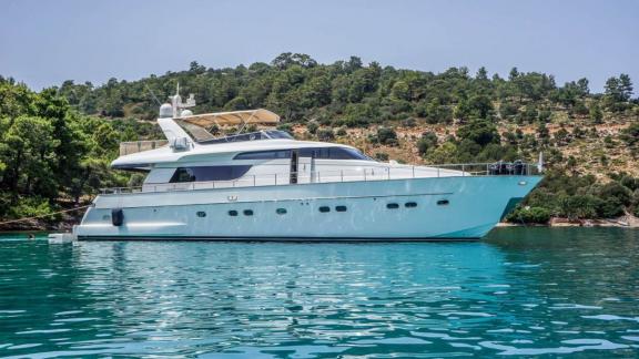 Motoryacht Kuum vor Anker in Bodrum, im Hintergrund grüne Natur.