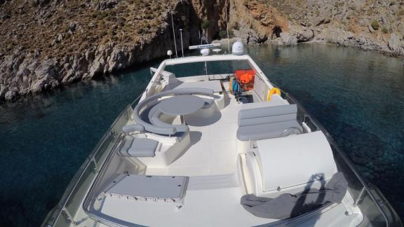 The upper deck of the motor yacht Mary features comfortable seating areas, anchored in a cove.