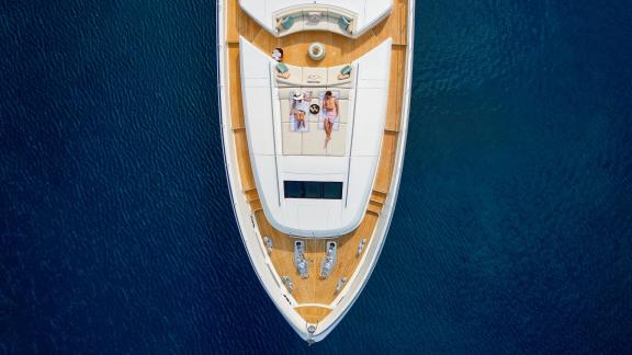 Die Princess 40M liegt ruhig im Meer, Gäste entspannen am Bug in der Sonne.