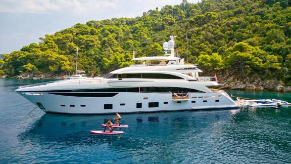 Die Princess 40M liegt ruhig vor Anker, Gäste genießen Stand-Up-Paddling.