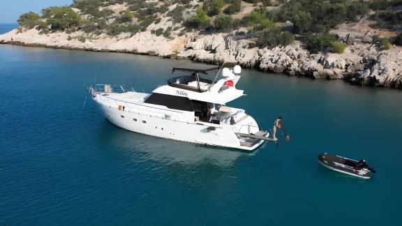 The motor yacht Niloş is seen moored in a tranquil cove.