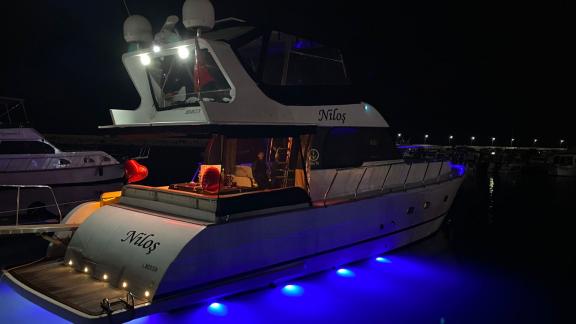 The motor yacht Niloş is anchored in the port with night lights on.