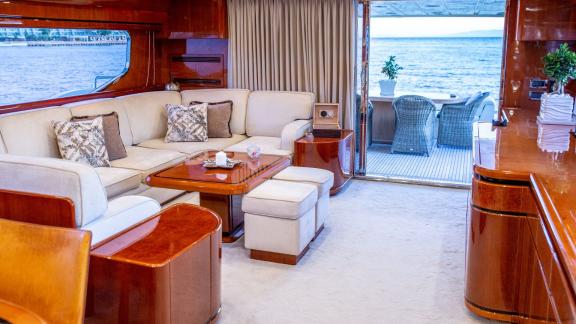 Luxuriös eingerichtetes Wohnzimmer auf der Yacht Pareaki mit Meerblick im Hintergrund.