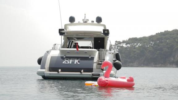 Die Yacht Sfk ist im Meer vor Anker, davor ein rosa aufblasbarer Flamingo, ruhige Landschaft.