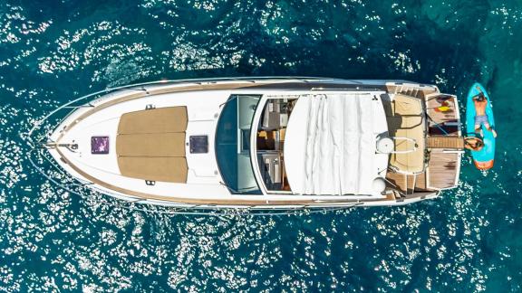 Die Motoryacht Silencio liegt bei Mallorca Touristen paddeln daneben durchs Wasser.