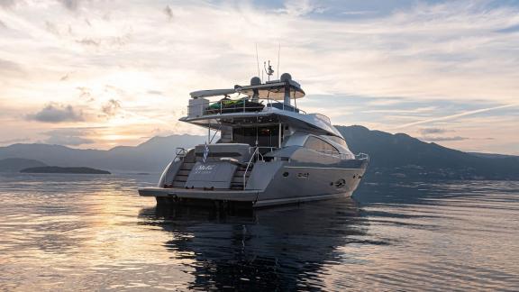 Stela 117 yacht seen on calm waters with mountains at sunset in the background.