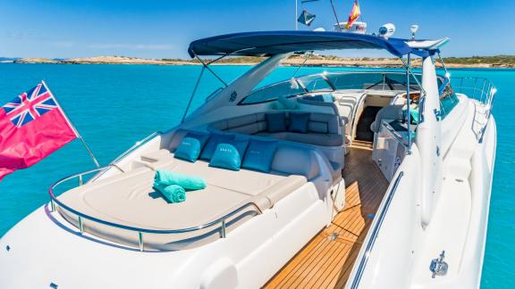 Anchored in Ibiza, the yacht features a sunbed, turquoise towels and a comfortable seating area at the back.