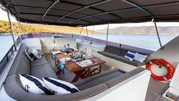 The flybridge upper deck of Sveti Sky offers spacious seating areas and a dining table with sea view.