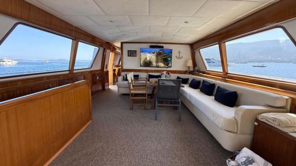 The main salon of Sveti Sky features a large U shaped sofa, dining table and panoramic sea view windows.