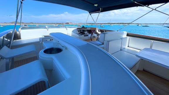 The flybridge of motor yacht Riva 21 features a helm station and a seating area.