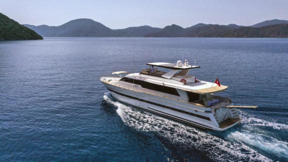 The motor yacht Vega elegantly cruising on the blue waters between mountains in Göcek.