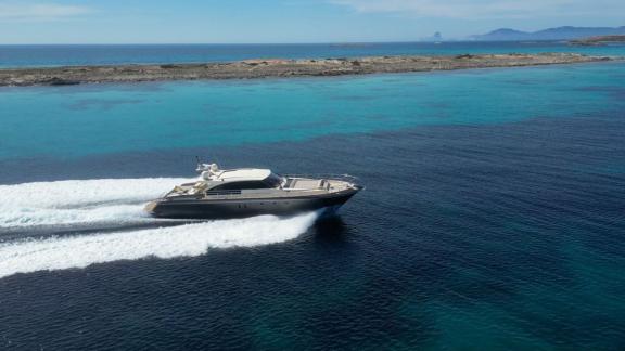 Motor yacht Vintage cruising fast through turquoise waters with views of surrounding islands.