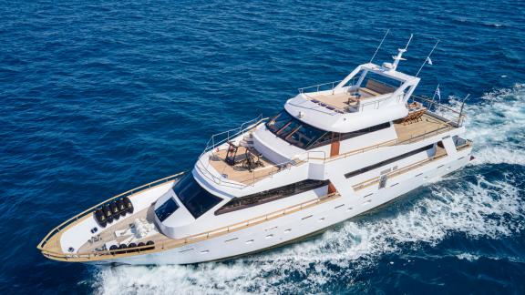 The motor yacht Wide Liberty cruising at full speed through the clear waters of the Mediterranean.