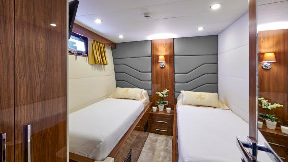 Comfortable twin cabin of the motor yacht Wide Liberty with two single beds and stylish decor.