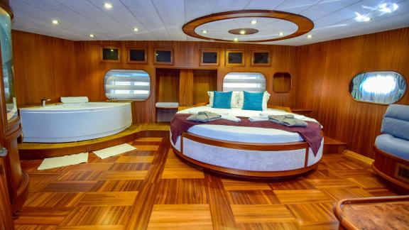 A spacious cabin on the gulet 'Ugur' with a round bed and a bathtub.