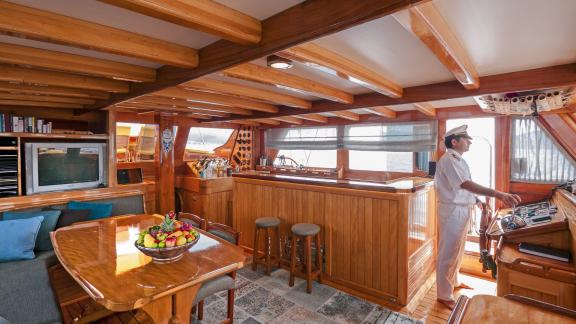 Captain steering the Gulet Nikola. Cozy lounge and dining area for socializing onboard.