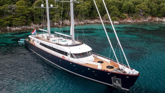 The Motor Sailor Nocturno anchored near the wooded coast, surrounded by turquoise water.