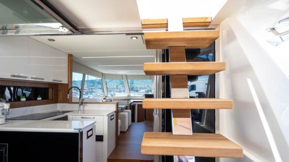 View of the stylish kitchen and living area of the Panta Rei motor yacht with an elegant wooden staircase.