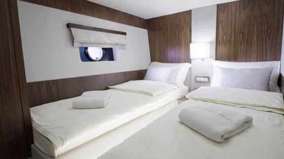 Modern twin-bed bedroom on the Panta Rei motor yacht with stylish wood decor and cozy atmosphere.