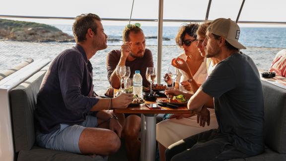 Friends enjoying food and conversation during a sea cruise from Athens in Greece.