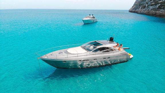 Motoryacht Byblos 3 liegt vor Ibiza vor Anker. Zwei Personen sitzen am Heck.