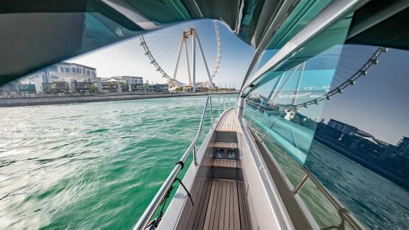 Enjoy the stunning city view from the side deck of Pershing 5X Grey with Dubai daily yacht rental services.