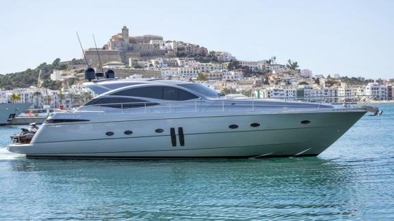 Die graue Yacht Optimum liegt vor Ibiza. Im Hintergrund erkennt man die Altstadt und weiße Häuserfassaden.