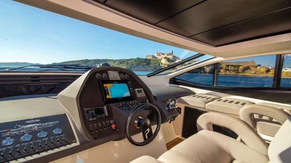 Der Steuerbereich der Yacht bietet digitale Anzeigen und große Fenster. Im Hintergrund liegt die Altstadt von Ibiza.