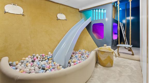 Colorful playroom with slide and ball pit for children.