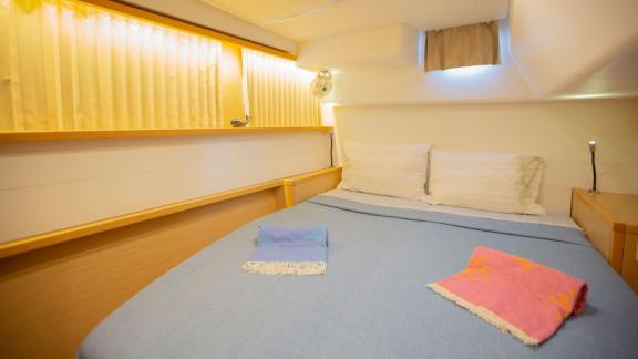 A bright and cozy cabin on a Lagoon 560 catamaran, featuring a comfortable double bed and soft lighting, creating a rela