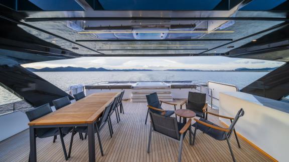 Evita power catamaran features a spacious flybridge with dining table, lounge seating and panoramic sea views.