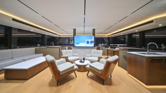 Evita power catamaran features a panoramic saloon with lounge seating, TV unit and open galley.