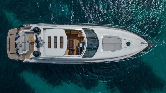 Deckansicht der Motoryacht Shadow vor Anker an Ibizas Küste, aus der Luft.