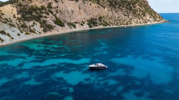 Motoryacht Shadow liegt vor Anker in einer naturbelassenen Bucht Ibizas.
