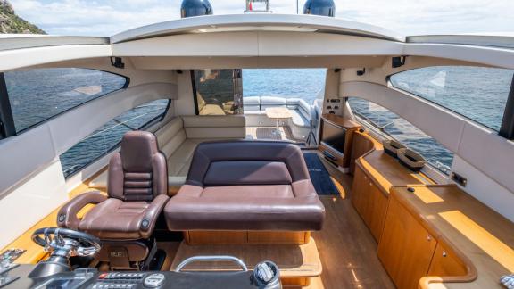 Großzügiger Salon und Steuerstand der Motoryacht Shadow vor Anker bei Ibiza.