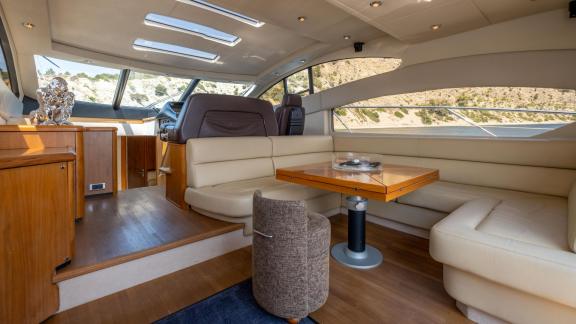 Bequeme Sitzecke und Esstisch auf der Motoryacht Shadow vor Anker bei Ibiza.