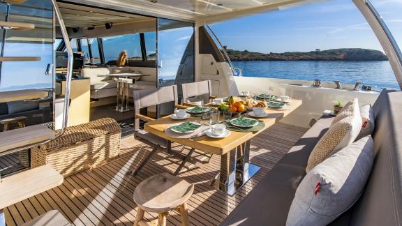 The aft deck of Blue M motor yacht in Mallorca features a fully set dining area.