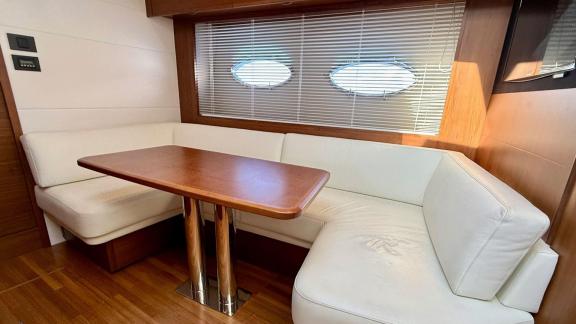 Among Monaco daily yacht charter options Belle Vie motor yacht shows interior with corner sofa and dining table.