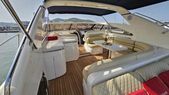 Ibiza'da demirli Sunshine motoryatının arka bölümünde konforlu oturma grubu ve masa bulunuyor.