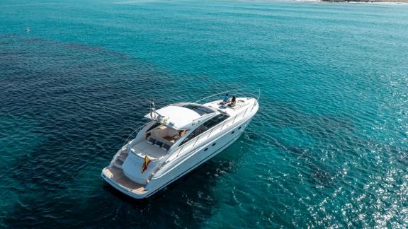 Excalibur motoryatı Ibiza'da günlük yat kiralama için sakin sularda demirlemiş halde görülüyor.