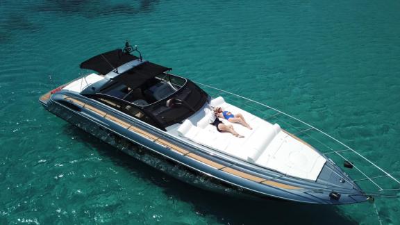 Ein Paar entspannt sich auf dem Vordeck der Motoryacht Este 2 im klaren Wasser von Mykonos.