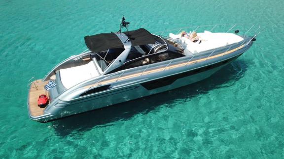Die Motoryacht Este 2 liegt in türkisblauem Wasser bei Mykonos; an Deck sind großzügige Liegeflächen klar zu sehen.