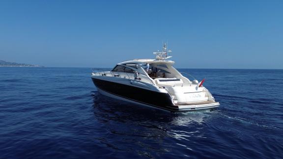Among Monaco yacht rental options Nous motor yacht is seen from rear cruising on calm sea.