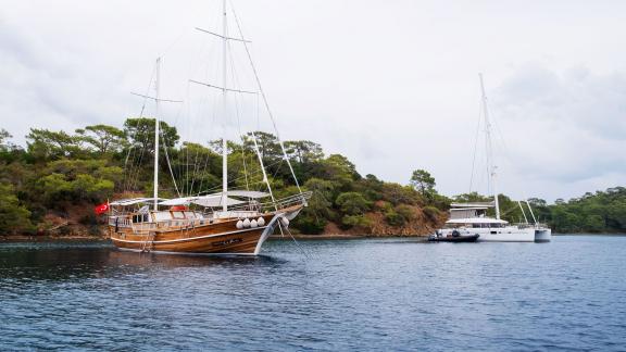 The Gulet Pronto White anchored in a picturesque Turkish bay, surrounded by natural beauty, perfect for up to 12 people.