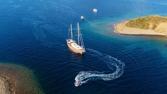 Die Gulet Pronto White segelt in der Nähe einer türkischen Insel, begleitet von einem Motorboot, ideal für bis zu 12 Per