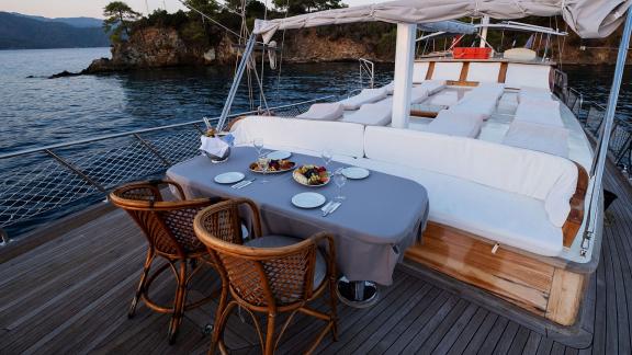 A stylishly set table on the deck of Gulet Pronto White, perfect for dinner at sunset, surrounded by calm waters.